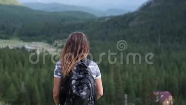 穿着短裤背包的女旅行者站在山顶，举起双手。 目标的实现。 慢慢慢慢
